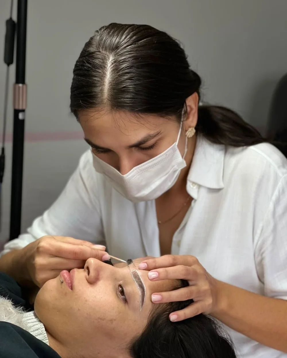 Luana atendendo uma cliente no design de sobrancelhas